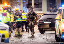 Beväpnad insatsstyrkam räddningstjänstpersonal och ambulans räddningsfordon med blåljus.