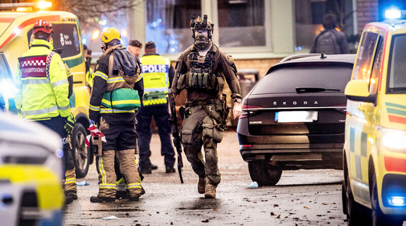 Beväpnad insatsstyrkam räddningstjänstpersonal och ambulans räddningsfordon med blåljus.