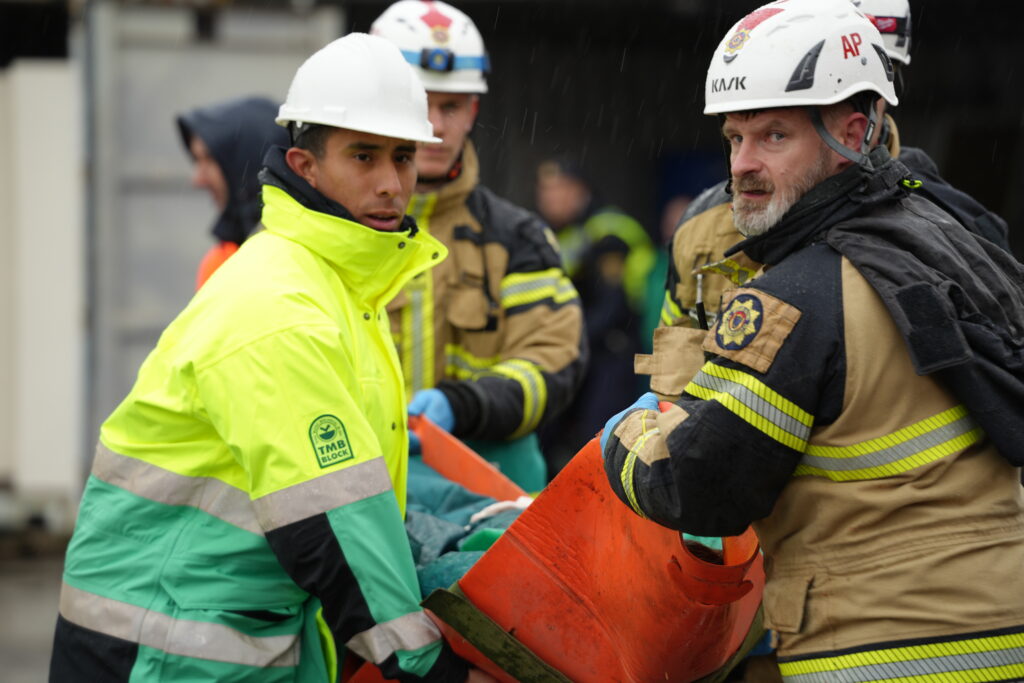 Brandman och ambulanssjukvårdare bär person.
