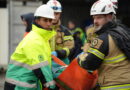 Brandman och ambulanssjukvårdare bär person.