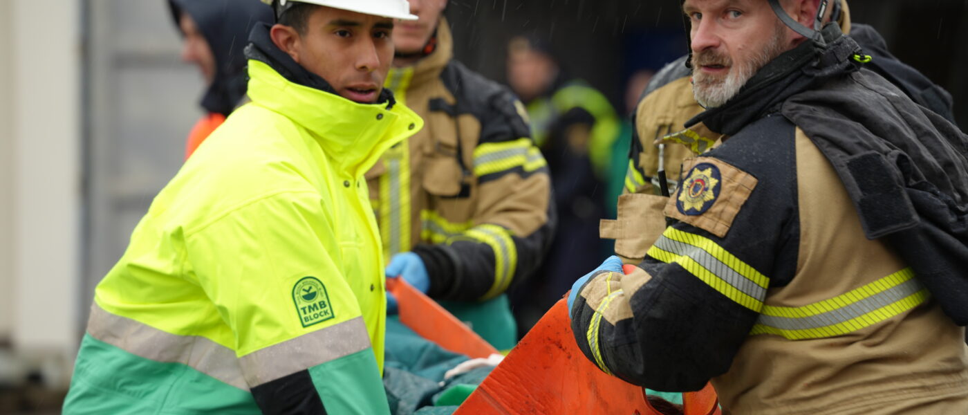 Brandman och ambulanssjukvårdare bär person.