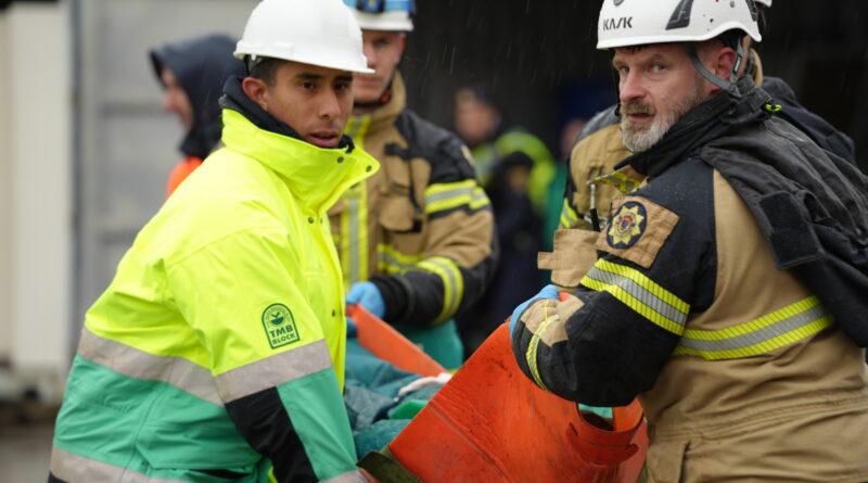 Brandman och ambulanssjukvårdare bär person.