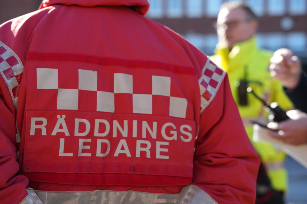 Ryggen på Räddningsledare, människor syns i bakgrunden