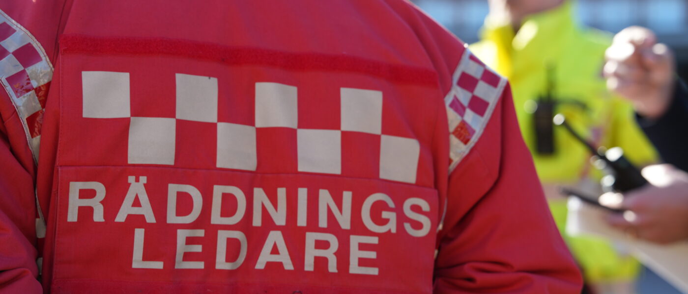 Ryggen på Räddningsledare, människor syns i bakgrunden