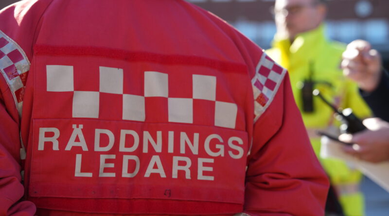 Ryggen på Räddningsledare, människor syns i bakgrunden
